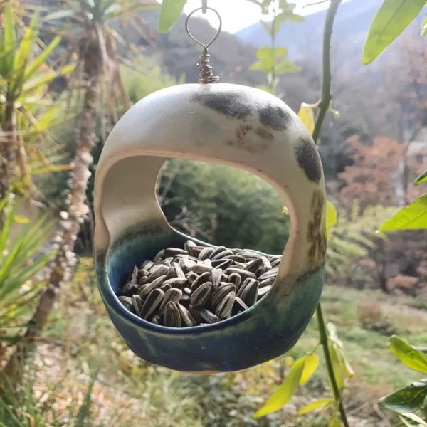 Mangeoire à oiseaux en grès suspendue dans un jardin